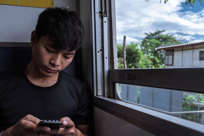 Young man using smart phone in train