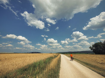 Road amidst field against sky