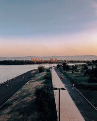 Road by river against sky at sunset