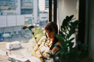 Thoughtful young woman sitting by window
