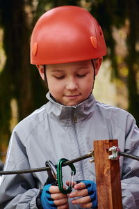 Boy in a helmet fastens a safety carbine to the rope.