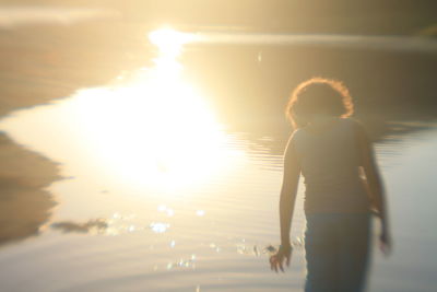 Man standing at beach against sky during sunset