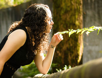 Midsection of woman holding plant while sitting outdoors