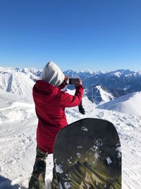 A girl taking a picture of mountains