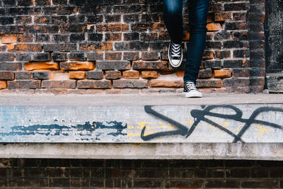 Low section of man standing by brick wall