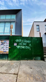 Graffiti on building against sky in city