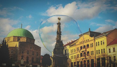 Low angle view of building seen through bubble against cloudy blue sky