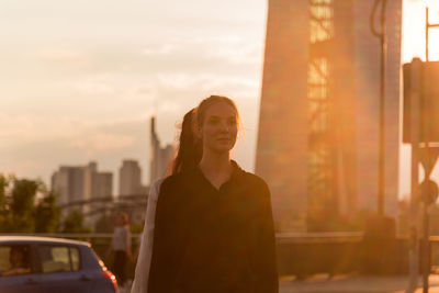 Female friends standing against bridge in city during sunset