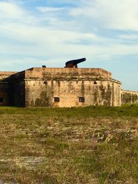 Old ruins on field against cloudy sky