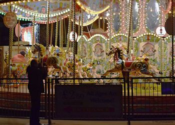 Illuminated carousel in amusement park at night