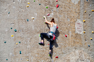 Full length rear view of woman climbing wall