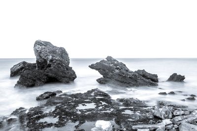Rocks in sea against clear sky