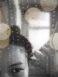 Close-up of woman seen through wet window