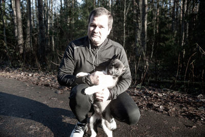 Portrait of man with dog against trees in forest