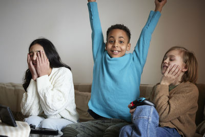 Children playing video games at home and celebrating