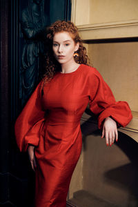 Portrait of beautiful young woman standing against red wall