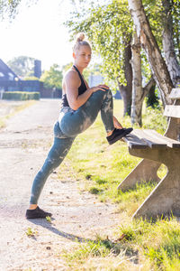 Side view of young woman exercising on field