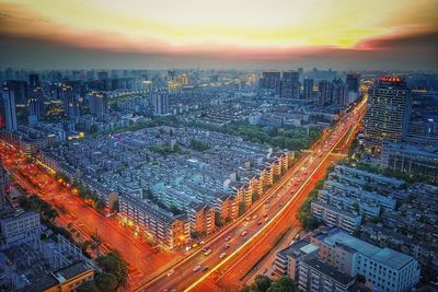 High angle view of city lit up at sunset