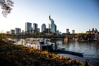 Modern buildings by river against clear sky