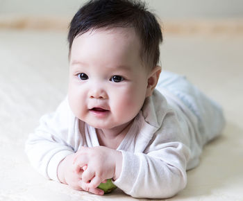 Close-up portrait of cute baby boy lying down on floor