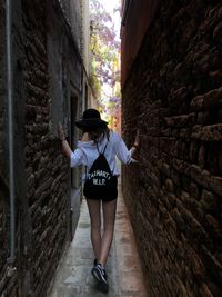 Rear view of woman standing on alley amidst buildings