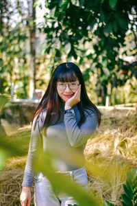 Portrait of young woman standing against plants