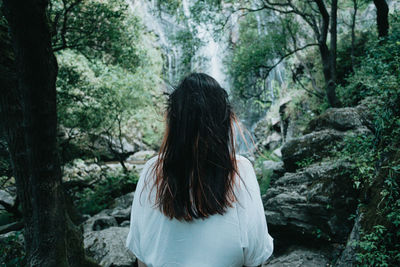 Rear view of woman standing against waterfall