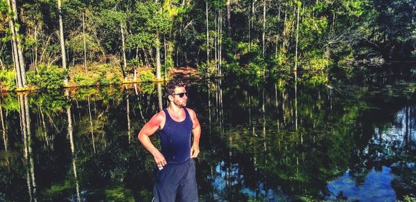 Young man standing by lake in forest