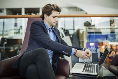 Businessman connecting plug to laptop at airport lobby