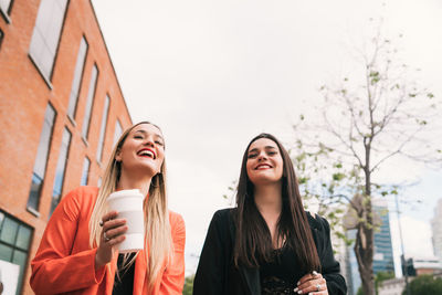 Portrait of smiling young woman holding coffee at park