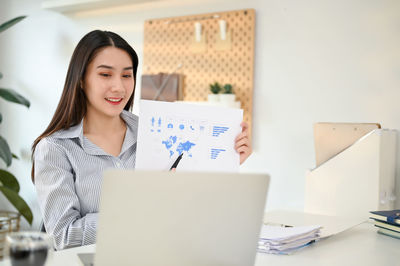 Portrait of young businesswoman using laptop at office