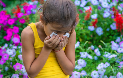 Girl sneezing with tissue on mouth