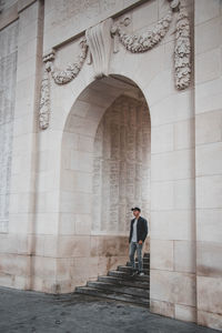 Full length of man standing on cross against building