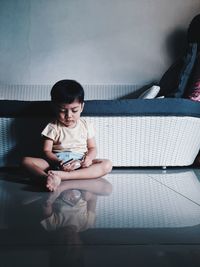 Full length of boy sitting on sofa