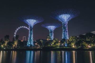Illuminated bridge over river against sky at night