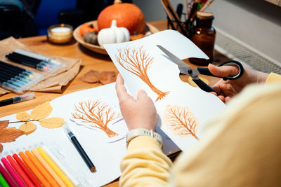 Autumn craft for adults. faceless portrait of woman drawing autumn trees with markers and cutting