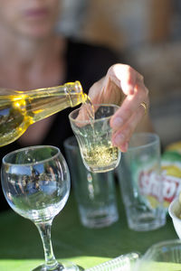 Midsection of woman pouring wine in glass on table