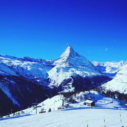 Scenic view of snowcapped mountains against blue sky