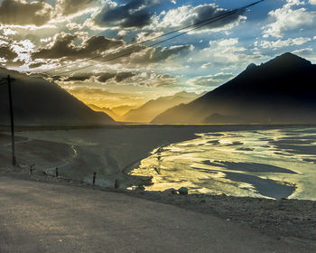 Scenic view of lake by mountains against sky at sunset