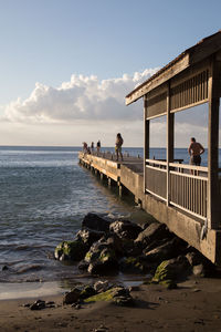 People standing on pier over sea