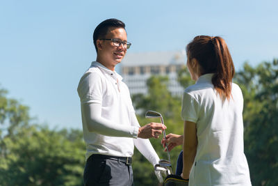 Full length of couple playing golf on field