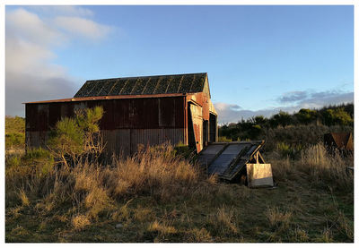 Abandoned house on field against sky