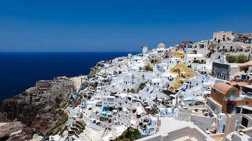 High angle view of townscape by sea against clear blue sky