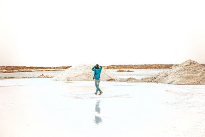 Full length of man walking in desert against clear sky