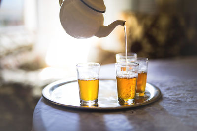 Pot pouring tea in glass on table