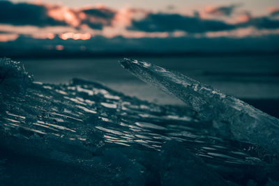 Close-up of frozen water in sea during sunset