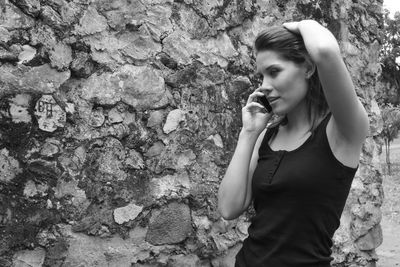 Young woman standing by stone wall