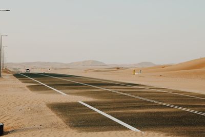 Road by desert against clear sky