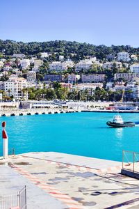 Scenic view of sea by city against clear blue sky