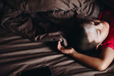 High angle view of boy sleeping on bed at home